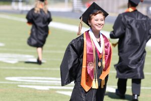 student smiling in cap and gown at graduation