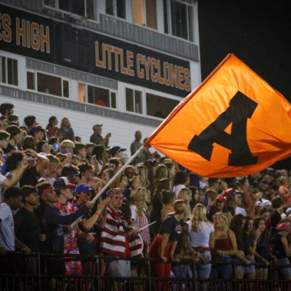 Student waves the A flag for Ames over the student crowd.